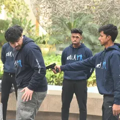 A gun to your back is a worst-case scenario, and I train you for it. This image shows a gun defense drill, focusing on how to turn, redirect the weapon away from your body, and gain control when you have no other choice.