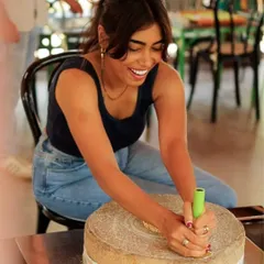 A guest tries her hand at a traditional grinding stone, a unique and mindful activity connecting to village life.