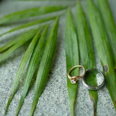 The wedding rings, captured in a natural setting on a palm leaf, symbolizing a fresh and organic start to a new life.
