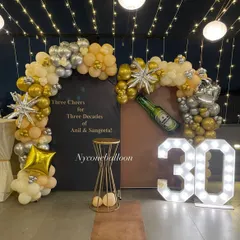 Celebrating 'Three Cheers for Three Decades' with this custom 30th milestone party. The setup includes a personalized backdrop, gold and silver balloon arches, and large light-up marquee numbers.