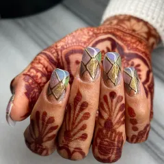 A closer view of the multi-tone chrome and gold geometric nail art. The precise line work and iridescent finish showcase a high level of detail and artistry.