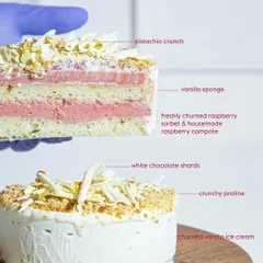 A detailed look at the layers of our Vanilla Raspberry ice cream cake. It features vanilla sponge, fresh raspberry sorbet, house-made compote, and a pistachio crunch base, all encased in vanilla ice cream.