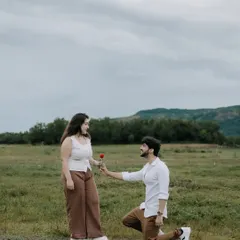 A classic proposal pose, with the groom on one knee offering a rose. Set against a wide-open field and distant hills, this shot feels both intimate and grand.