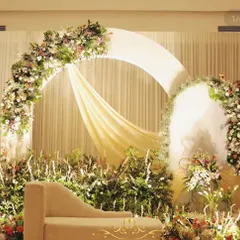 A variation of our popular circular arch design, this setup features a chaise lounge for the couple, surrounded by a sea of lush greenery and delicate flowers.