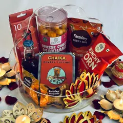 A stunning red-themed Diwali hamper, symbolizing good luck and prosperity. This gift basket is filled with red-packaged snacks from brands like Ekkam and Farmley, Chaika tea, and is surrounded by lotus-shaped diyas.