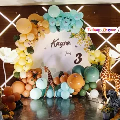 A detailed look at a safari-themed birthday for Kayra's third birthday. This setup includes a custom circular backdrop, a colorful balloon arch, and a variety of animal figures like a lion, giraffe, and zebra.