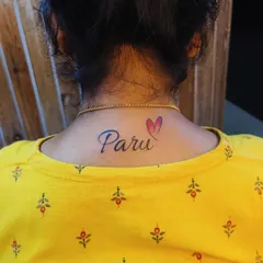 A "Paru" name tattoo placed on the back of the neck, finished with a small, color-filled heart. This is a popular and discreet placement for a personal tattoo.