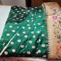 A close-up of the pre-pleated emerald green Banarasi saree for a Maharashtrian bride. The pleats are set and ready for box-folding, making it easy to store and transport before the event.