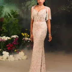 This is the Nuray Gown, defined by its intricate details. The design features a fitted mermaid silhouette with hand-embroidered patterns and elegant pearl tassels that drape over the shoulders.