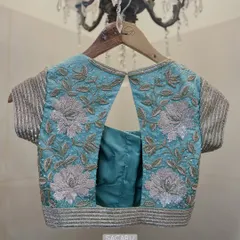 A sparkly floral embroidered blouse in a combination of light gold and silver detailing. The back features a simple keyhole cutout, letting the embroidery shine.