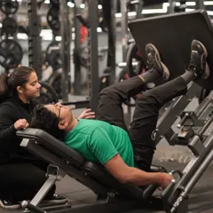 I ensure every client is safe and effective in their workouts. Here, a trainer spots a client on the leg press, providing encouragement and ensuring correct technique.