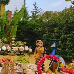 A detailed view of a traditional ceremony setup, featuring a classic South Indian doll next to a peacock figure. The space is filled with fresh fruits, flowers, and dry fruits as offerings, reflecting our attention to cultural details.