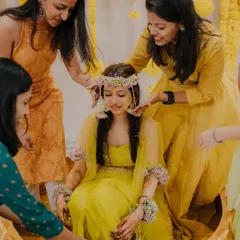 A beautiful moment during the Haldi ceremony as the bride's friends lovingly place a floral crown on her head.