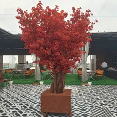 A magnificent artificial red blossom tree stands as the centerpiece of this rooftop restaurant. This statement piece adds a dramatic pop of color and sophistication, perfect for creating a memorable ambiance for events and dining.