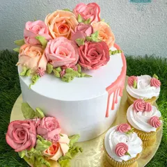 This cake and cupcake set is adorned with a cascade of hand-piped whipped cream roses in shades of peach and pink. It's a testament to our skill in creating fully edible, beautiful floral designs.