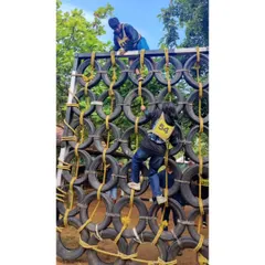 Participants tackling a tire wall obstacle. Our leadership camps involve challenging physical activities that build confidence.
