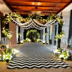 This striking black-and-white themed entrance creates a bold statement. A chevron-patterned carpet leads guests through a floral archway, setting a modern and sophisticated tone for the event.