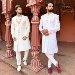 We create coordinated custom outfits for couples. Here, both grooms are in elegant white embroidered sherwanis, tailored for a perfect fit, ideal for a sophisticated wedding ceremony or a pre-wedding photoshoot.