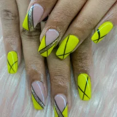 Sharp, modern, and geometric. This design uses a vibrant yellow base and adds a dynamic pattern of intersecting black lines. Accent nails with a nude base and a touch of glitter complete this edgy look.