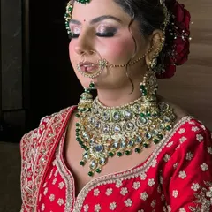 A close-up of a classic North Indian bridal makeup look. The focus here is on the detailed eye makeup with a silver and black smokey effect, perfectly complementing the heavy kundan and emerald jewelry.