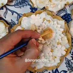 Here you can see my process of hand-painting the golden accents onto a floral urli candle. This final touch adds a layer of luxury and makes each piece unique.