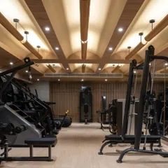 The gym at Be Well, where the architectural language of the rest of the center continues. The coffered wooden ceiling with integrated lighting creates a warm, uplifting atmosphere for exercise.