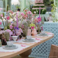 A beautiful tablescape from the 'Mayfair Luncheon', featuring floral-patterned china, pastel flowers, and elegant glassware. The setting was designed to feel like a garden tea party.