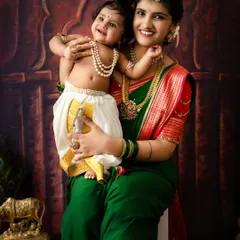 A sweet and happy portrait of a mother holding her smiling baby Krishna. The genuine smiles and traditional attire make this a perfect Janmashtami keepsake.