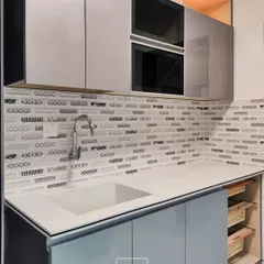 This utility area is designed for maximum efficiency, featuring built-in ovens, a deep sink, and open shelving with wicker baskets for easy-to-access storage. The mosaic backsplash adds a decorative touch.