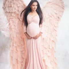 Live out a fantasy with our angel wing sessions. This ethereal portrait features large, feathery wings and a soft pink gown, creating a magical and heavenly image of motherhood.