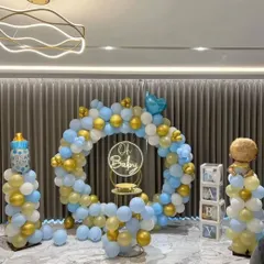 This "Oh Baby" themed baby shower is a classic and elegant choice. The setup features a full balloon ring in a soft blue, white, and gold palette, complemented by a neon sign, "BABY" blocks, and themed balloon pillars.