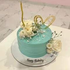 Another angle of this beautiful floral birthday cake. The combination of the textured frosting, fresh flowers, and gold accents makes it a sophisticated choice for any celebration.