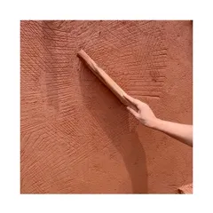 A close-up of the wooden 'Thappi' tool creating its signature strokes on the wall. This is a time-honored technique that we are passionate about preserving.