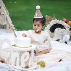 A gentle and sweet cake smash moment. This little one is delicately touching her first birthday cake in our outdoor boho-themed setup.