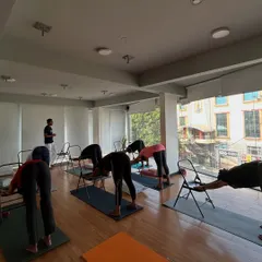 Students use chairs to practice a modified Downward-Facing Dog, which helps lengthen the spine without strain.