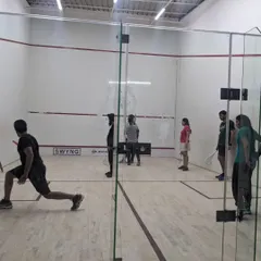 Players practicing lunges and movement on the court during a squash open house. Proper footwork is a fundamental skill we emphasize in all our training programs.