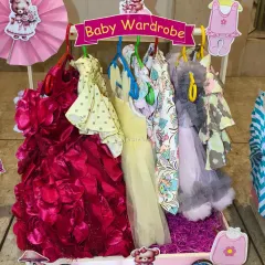 The 'Baby Wardrobe' for the twin baby girl, featuring a stunning red party dress and other pretty outfits.