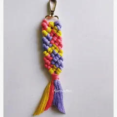 A macrame fishtail keychain in pretty lavender, coral, and yellow. This design is also called a mermaid keychain and can be used as a bag tag or charm.
