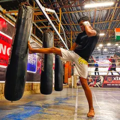 "Punch when you need to punch and kick when you need to kick." A student practices a powerful kick on the heavy bag, focusing on form and impact.