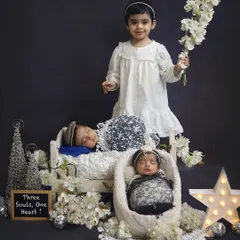 A beautiful trio of siblings. The older sister stands proudly with her newborn twin brother and sister in this carefully styled studio newborn photoshoot.