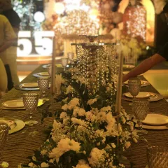 An elegant tablescape for a milestone celebration. The long table features a stunning floral runner with cascading crystals, creating a luxurious and celebratory atmosphere.