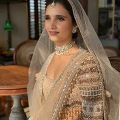 A side profile captured in beautiful natural light. This highlights the dewy finish on her skin and the intricate pearl and thread work on her sleeves.