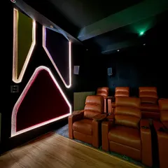Another angle of the custom cinema room, showing the multi-layered seating arrangement. Every seat gets a perfect view of the 180 inch screen, and the surround sound is calibrated to be immersive from every position.