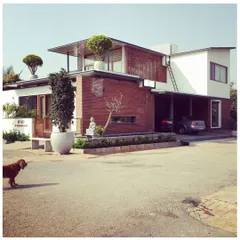 This Bengaluru residence showcases a blend of modern forms with natural materials like brick and wood. The design incorporates cantilevered roofs and large planters, integrating the building with its landscape.