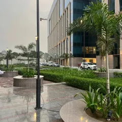 The same corporate campus viewed on a rainy day, showcasing the durability and year-round beauty of our landscape designs. The wet pavement reflects the ambient lighting and lush greenery, creating a tranquil scene.