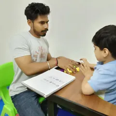 In our special education sessions, we focus on foundational academic skills. Here, a therapist works with a child on pre-writing exercises using tactile materials to improve grip and cognitive understanding before moving to paper.