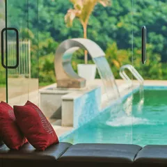 The view from a living room can be the most important artwork. Here, a large glass window frames the outdoor pool and a sculptural water feature, defining the space and connecting it to the serene landscape outside.