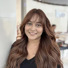 This look is a custom mix of coffee, chocolate, and chestnut tones. The result is a warm, rich brown that looks incredibly natural, complemented by bangs and soft waves.