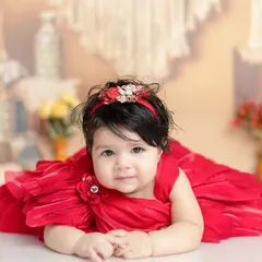 A beautiful six-month-old baby girl in a stunning red dress. The soft, bohemian-style background adds warmth without being distracting.