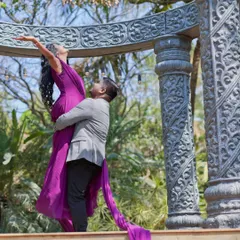 A dramatic and romantic pose from a pre-wedding shoot, with the bride's flowing purple gown creating a sense of movement and elegance.